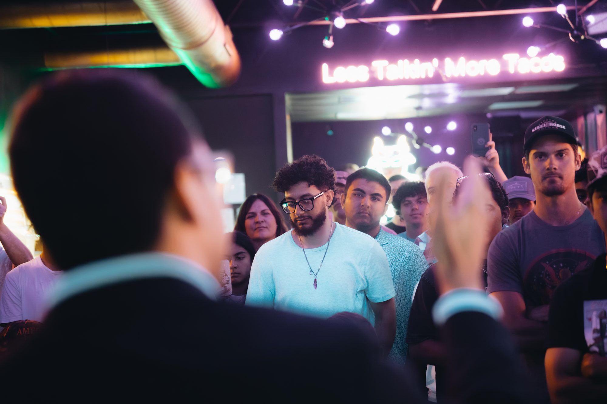 Candidate speaking to a crowd in a bar, seen from behind