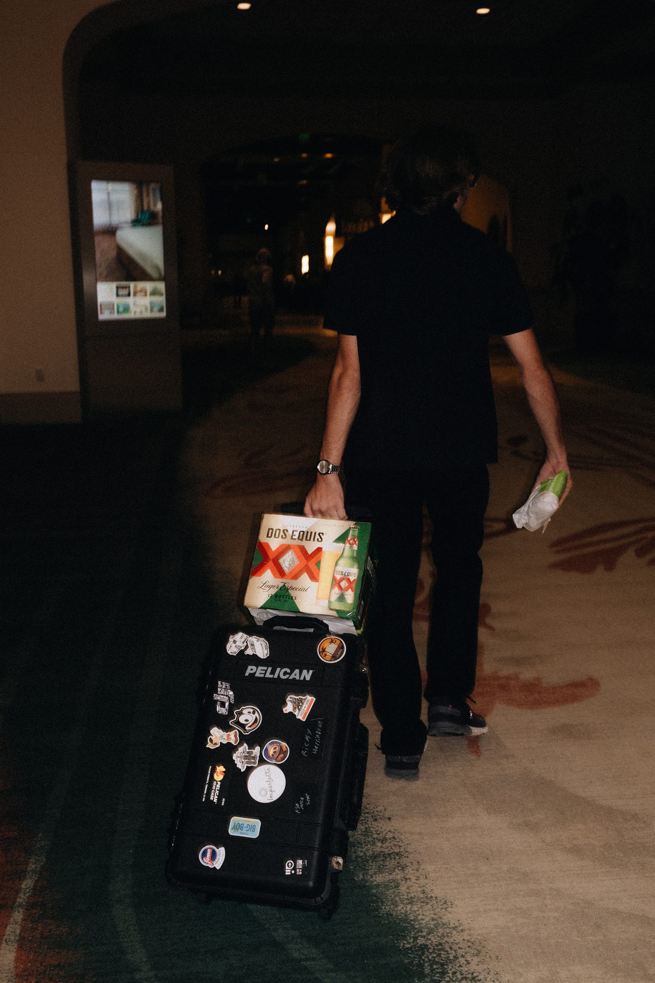 Crew member hauling cases through a hotel lobby at night