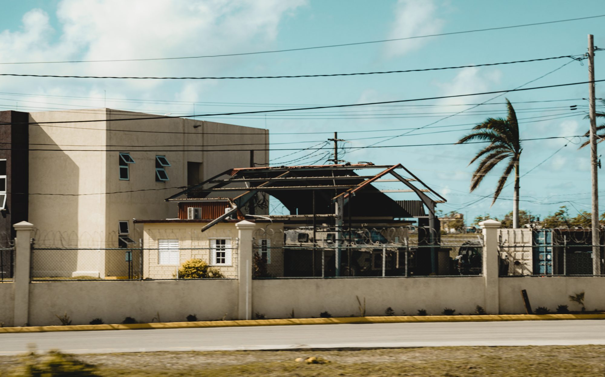 Damaged buildings along a roadside, one missing its roof