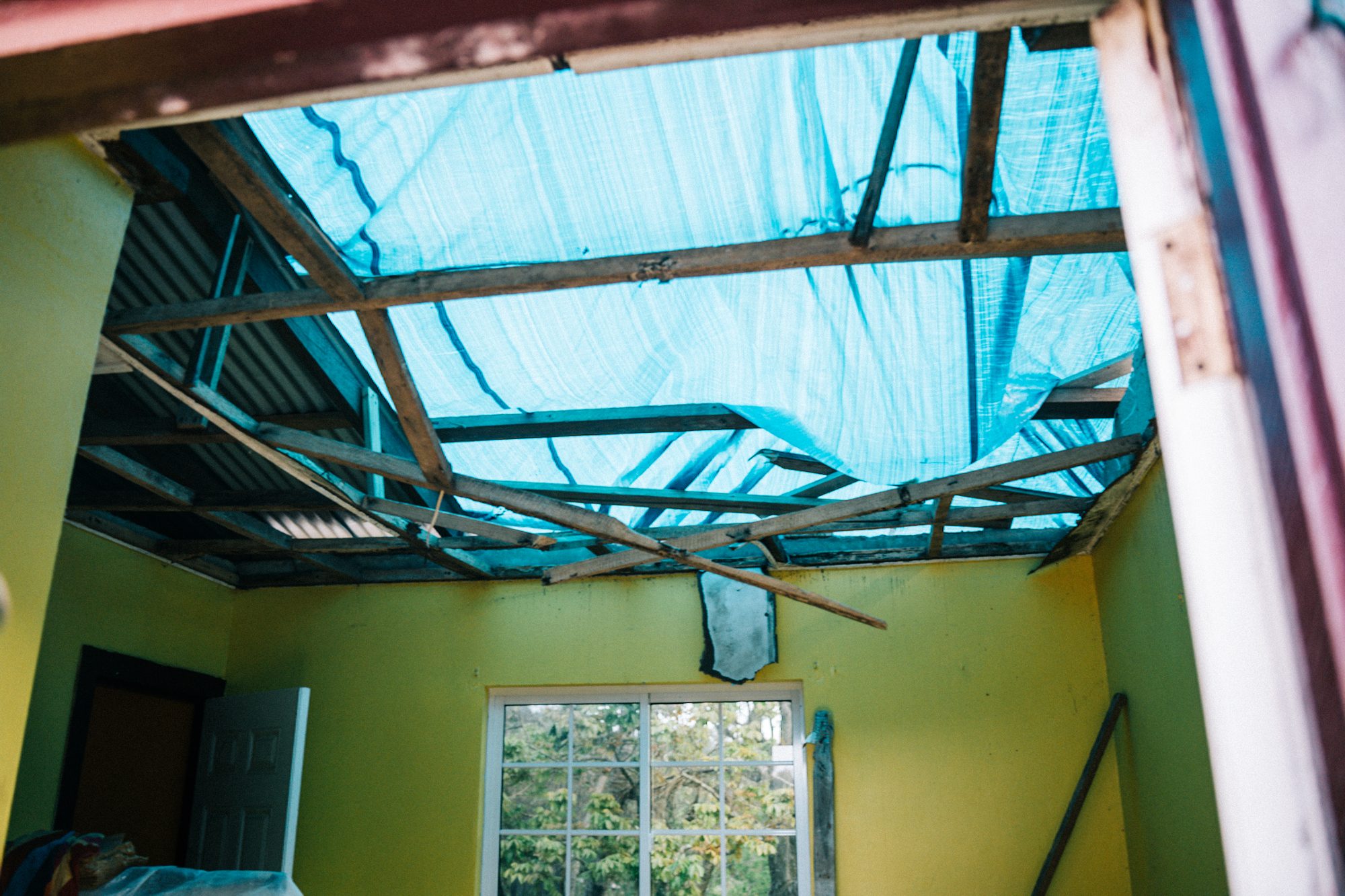 Classroom with the roof torn open, blue tarp overhead