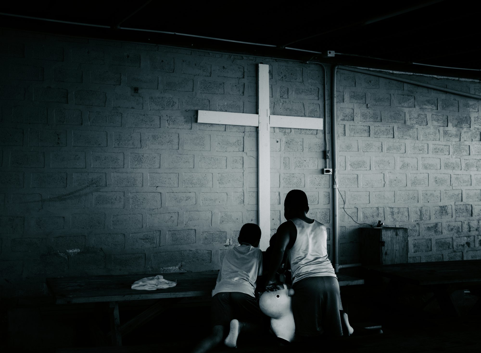 Two people kneeling in front of a cross on a church wall