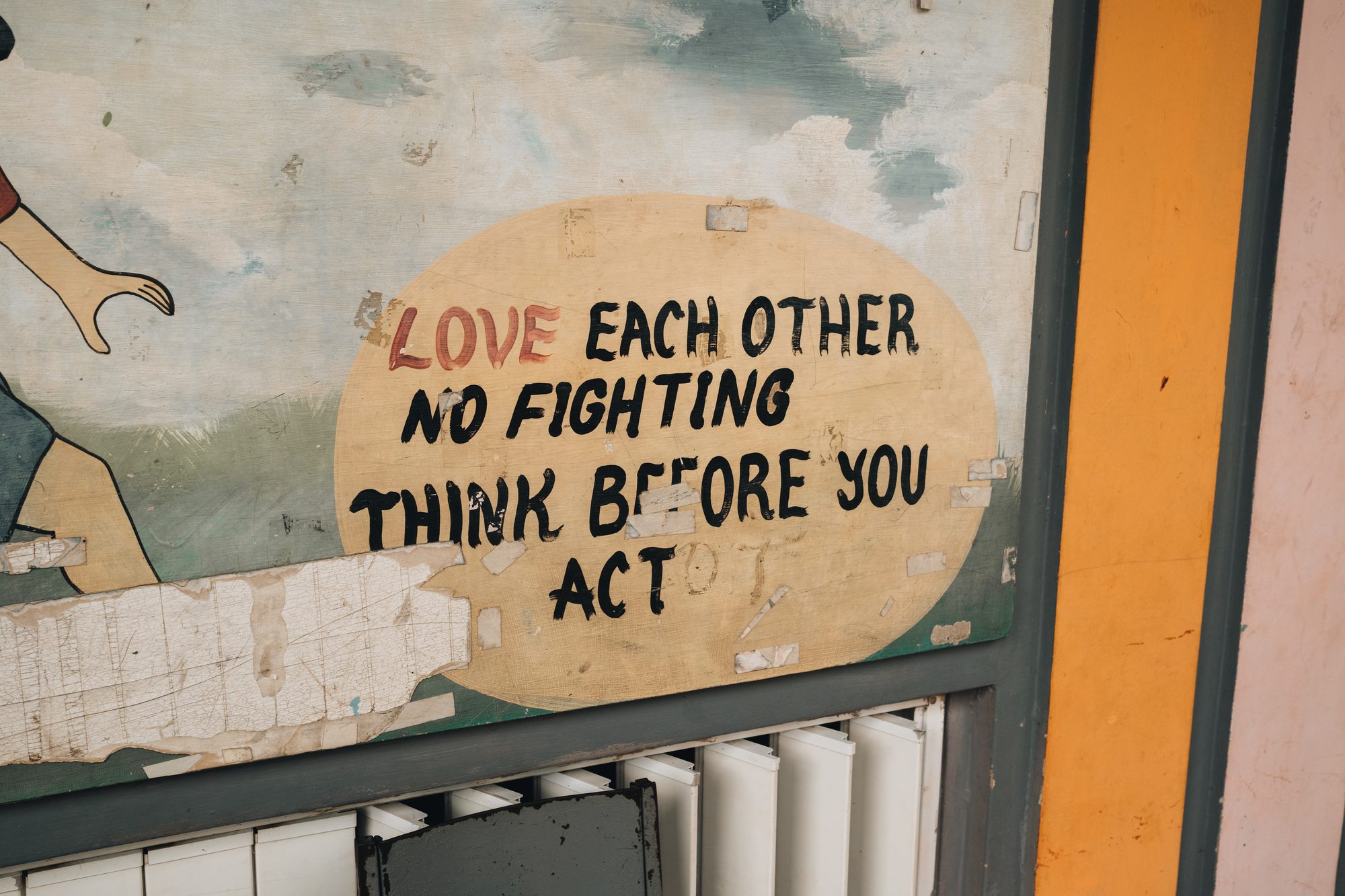 Painted mural that reads love each other, no fighting, think before you act