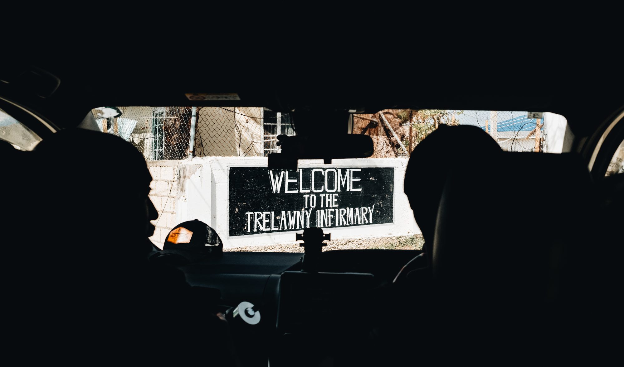 Welcome sign for Trelawny Infirmary through a car windshield