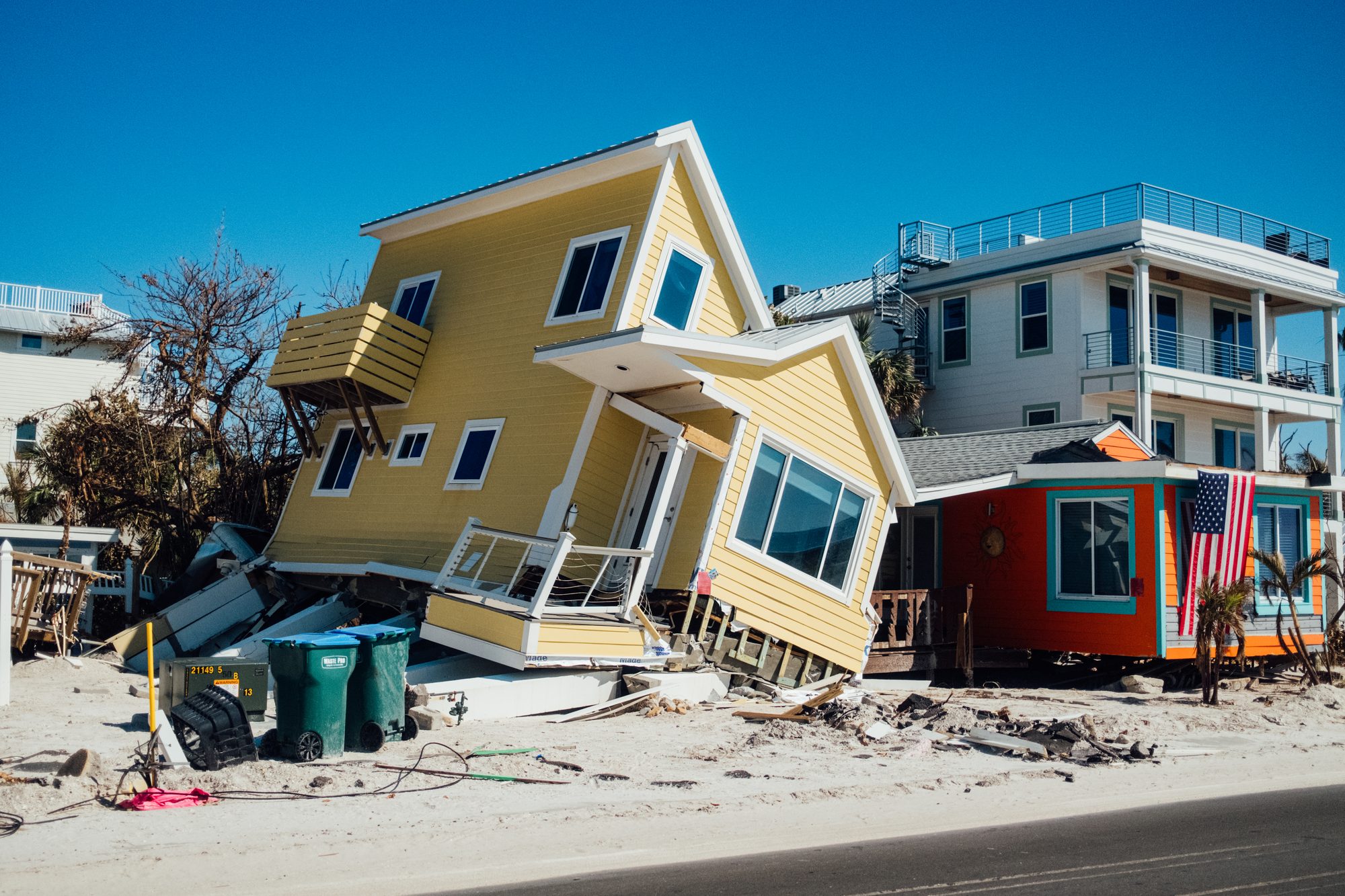 Yellow house knocked off its foundation and leaning