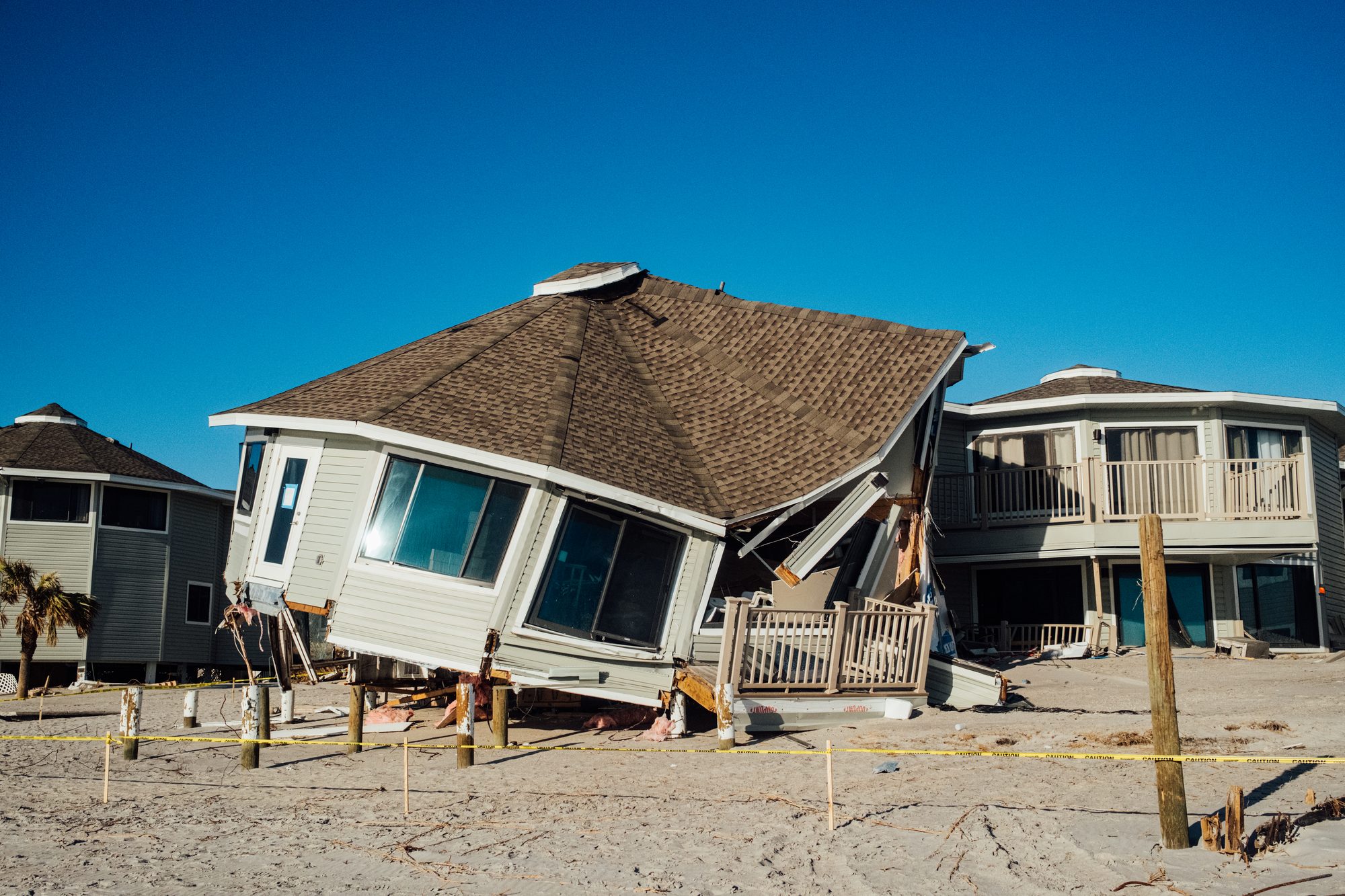 Beach house tilted off its pilings into the sand