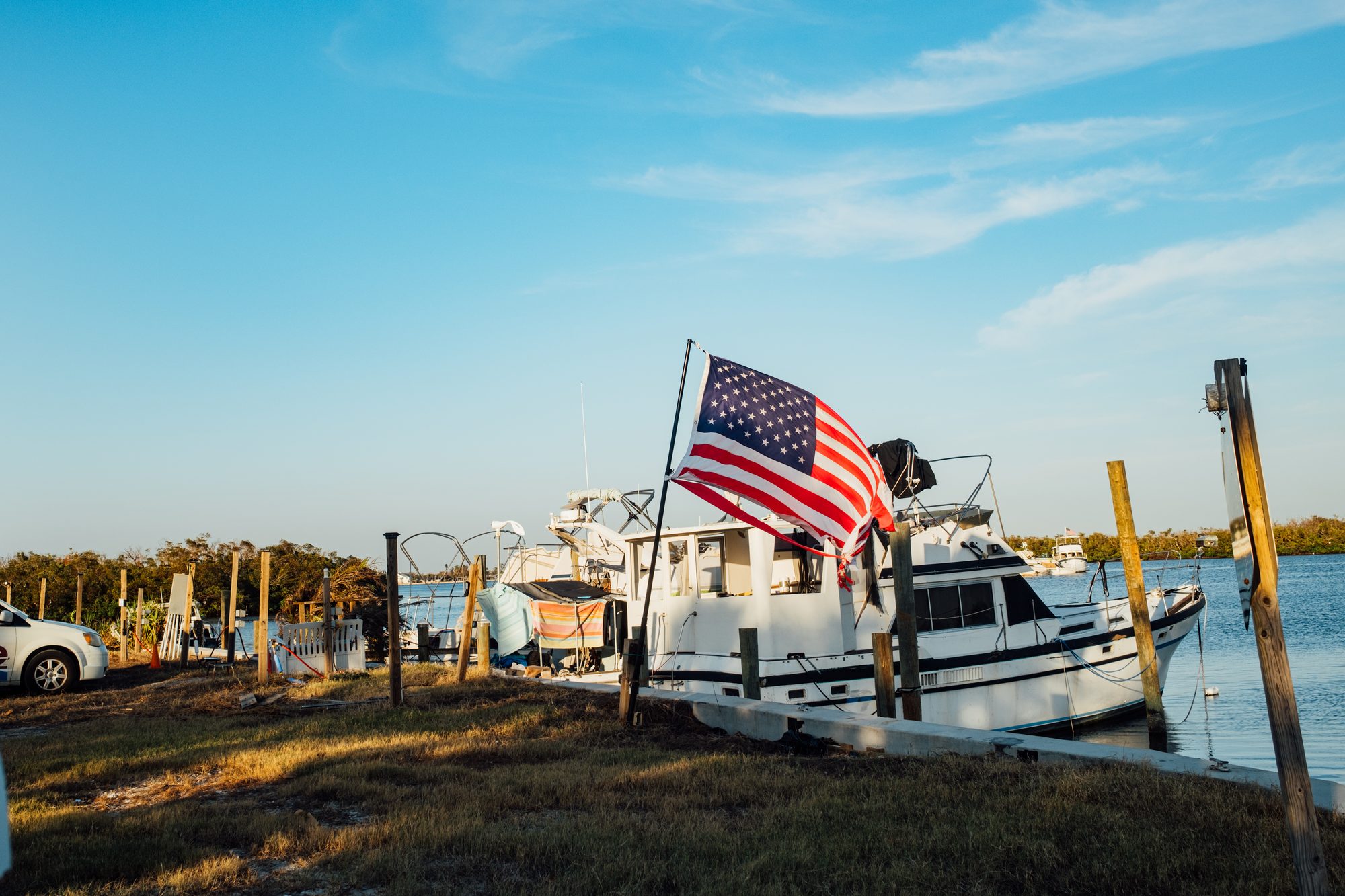 American flag flying over a damaged boat at a dock