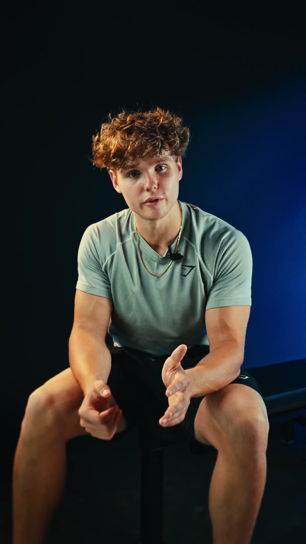Randall of Team GC Coaching sitting on a bench in the studio, talking to the camera with a small mic clipped to his shirt